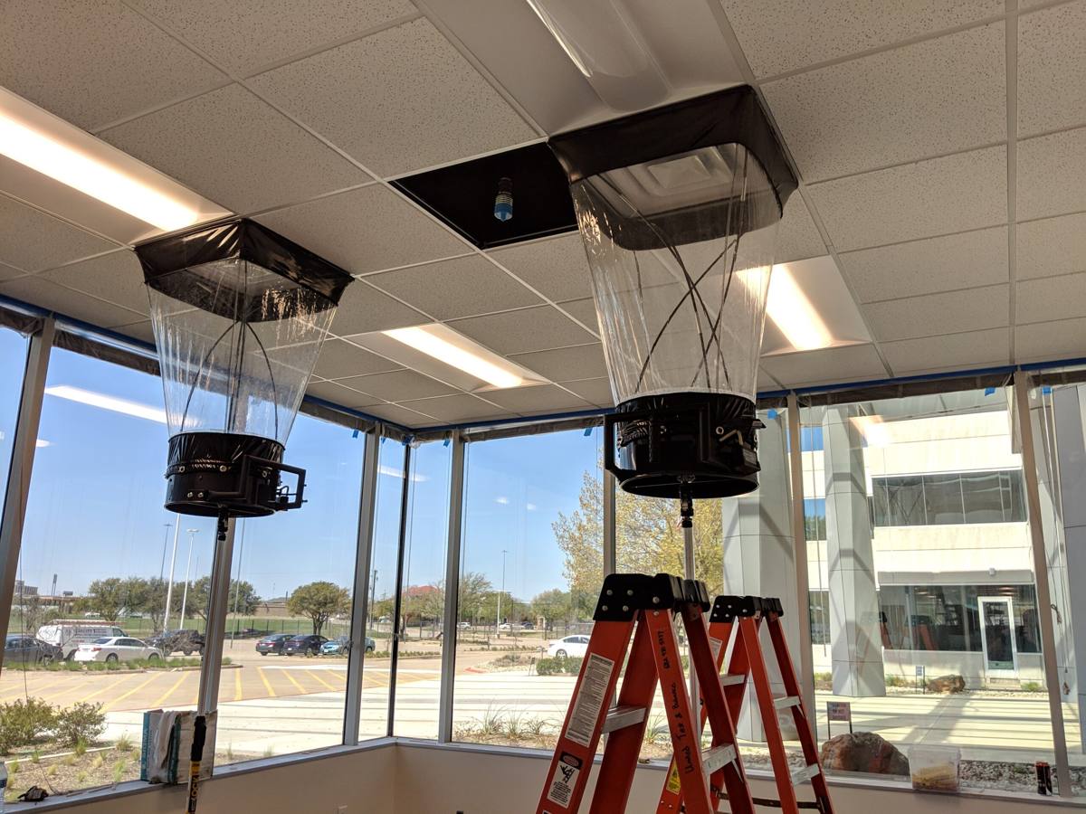 Capture hoods measuring airflow at ceiling diffusers